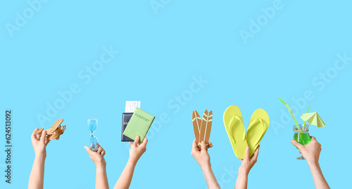 Many hands with beach accessories, passports and cocktail on blue background