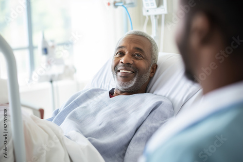 Smiling senior afro man lying on hospital bed with his son in background