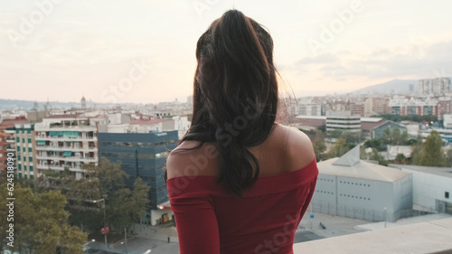 Close up, young woman standing on the balcony looking at the city at sunset, back view © Andrii Nekrasov