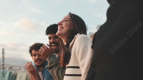 Close-up of young people, guys and girls friends standing hugging each other on the balcony looking at the beautiful views