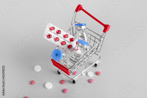 Mini shopping cart with different pills on grey background
