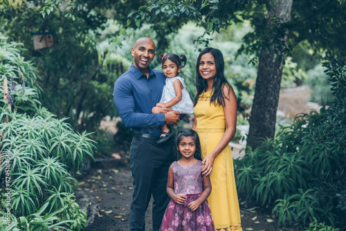beautiful indian family standing and smiling in the park with trees and greenery