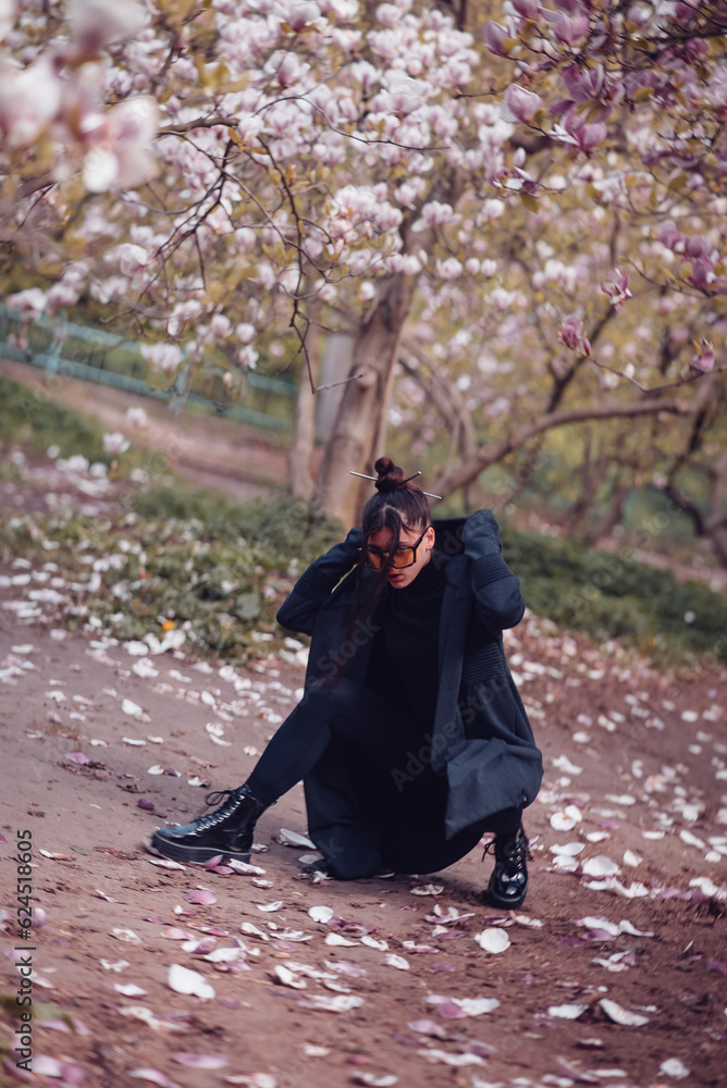 Dramatic young woman wearing black kimono and yellow glasses with cherry blossoms, sakura view Dramatic young woman wearing black kimono and yellow glasses with cherry blossoms, sakura view