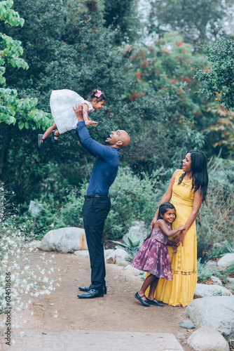Photography beautiful indian family with kids dad is throwing a child in the air  in the par