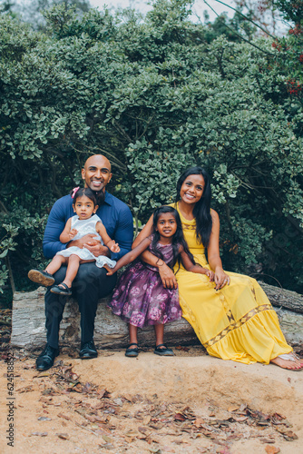 Canvas Print beautiful indian family sitting and smiling in the park with trees and greenery