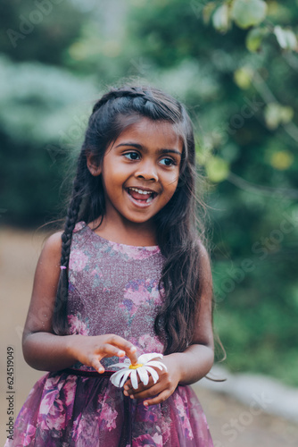 portrait of a beautiful indian little girl in the park with trees and greenery
