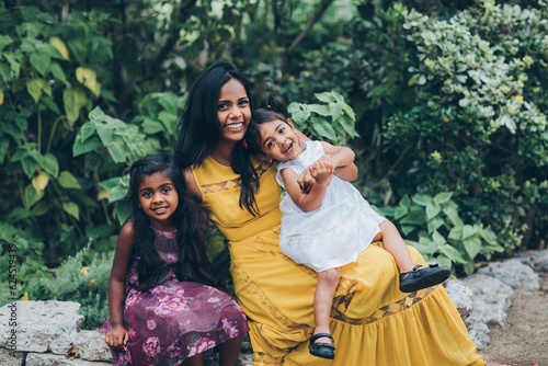 beautiful indian mother hugging her children daughter girl in the park with trees and greenery