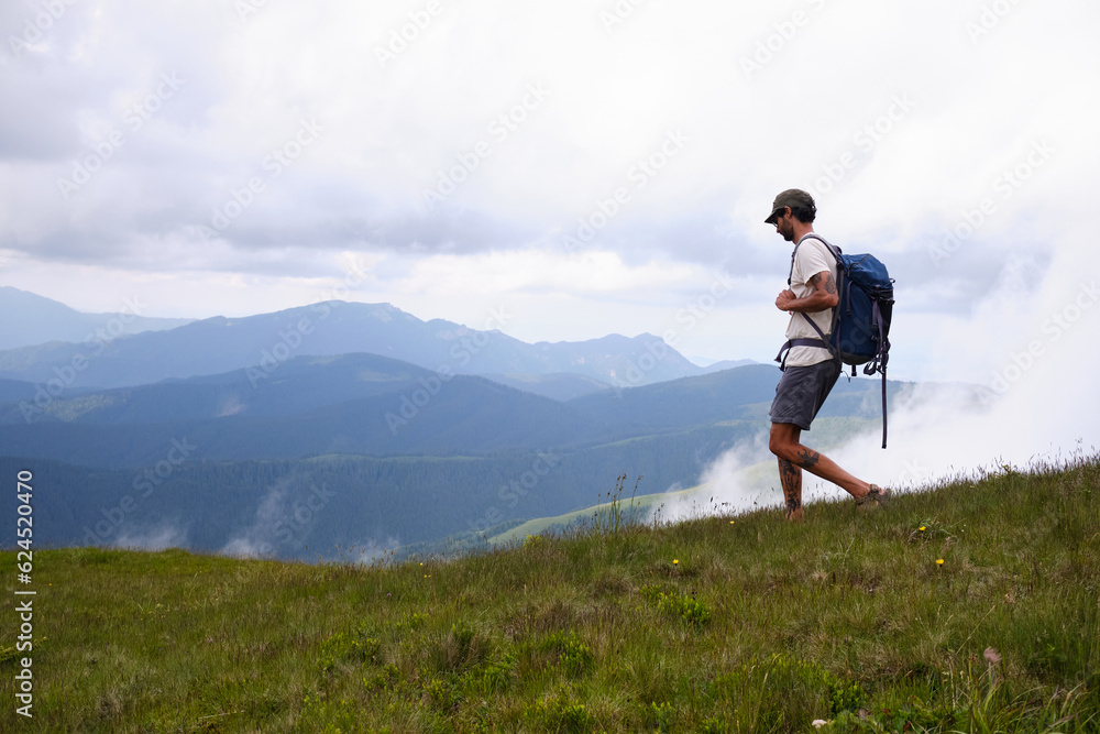 Naklejka premium Baiului Mountains trails. Man traveler with backpack is hiking in mountain.Traveling in nature.Rearview shot of a middle aged man hiking in the mountains. Bucegi natural park. 