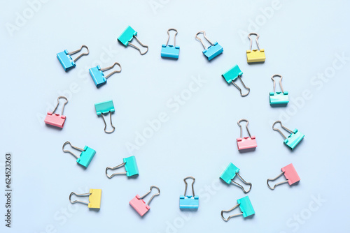 Frame made of colorful binder clips on light blue background