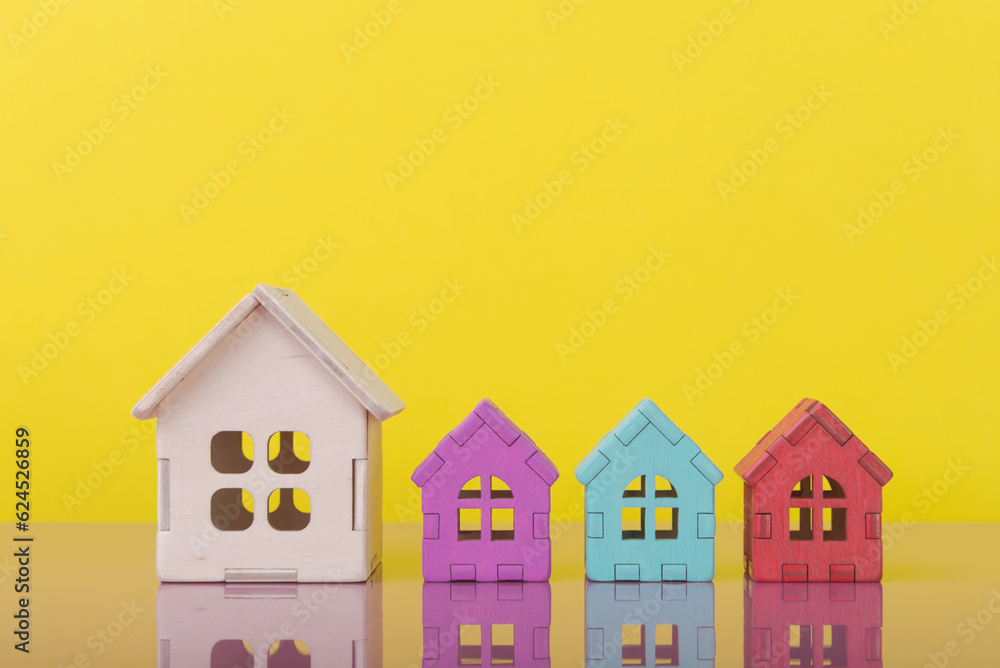 Blank and colorful wooden house models over yellow background with copy space. Multiple offers on your house.