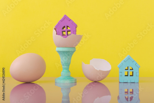 House models on eggshell over yellow background with copy space. New home buying photo