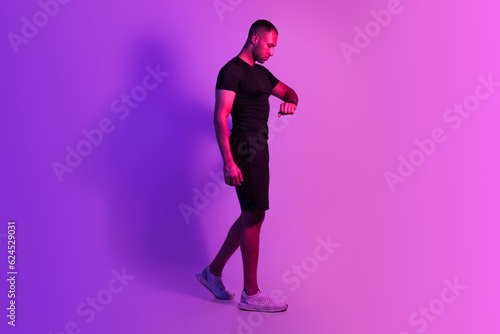Sporty African Man Walking Watching At Fitness Smartwatch, Purple Background