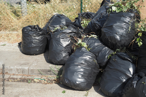 Black garbage bags stack on a park 