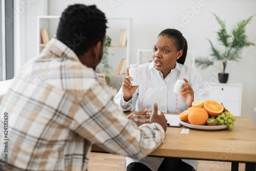 Canvas Print Attentive nutrition professional having talk with middle-aged male about food supplements in doctor's workplace