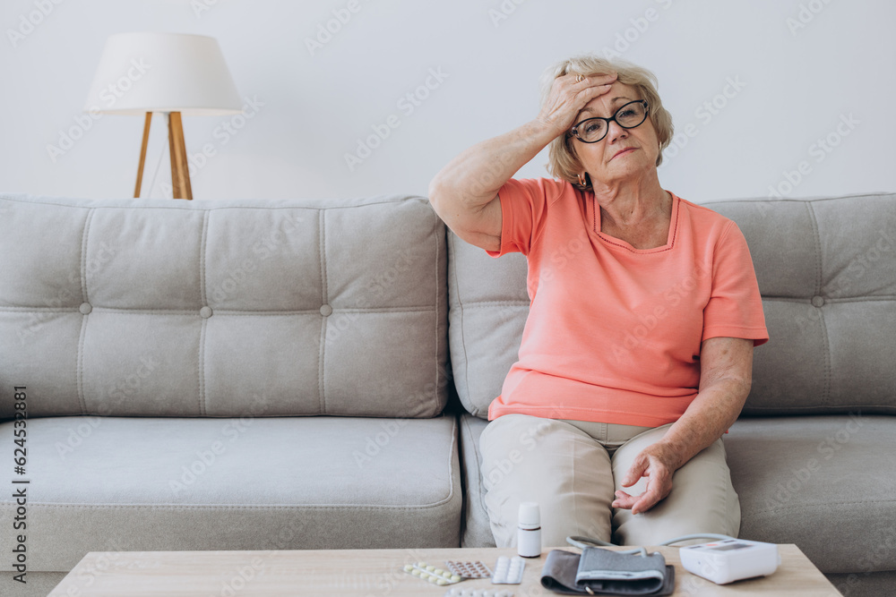Sick older woman take care for health, using sphygmomanometer for measure blood pressure, pulse and heart rate by self and takes medication at home.