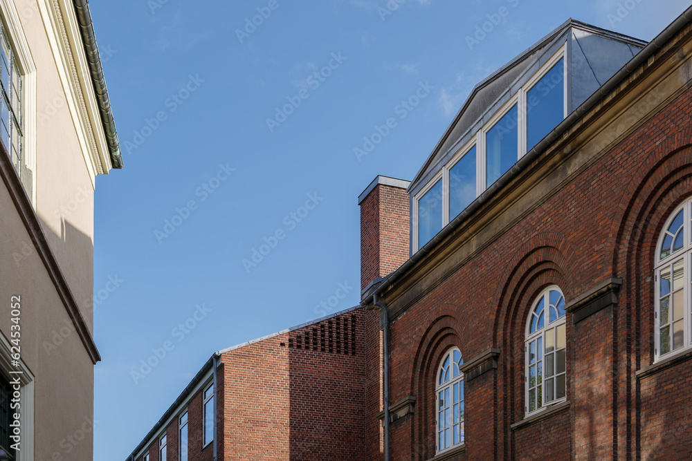 Selective focus and detail of industrial or factory brick facade with arch windows and rooftop in Europe. 