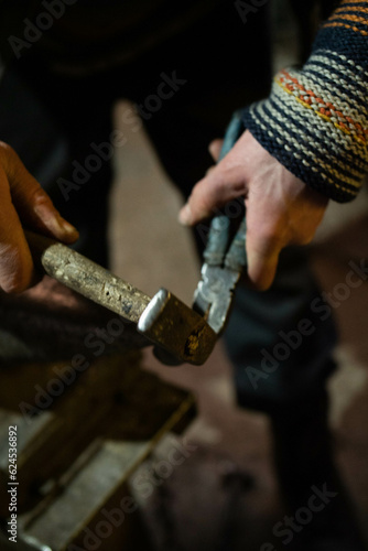 blacksmith's hands holding pliers and hammer