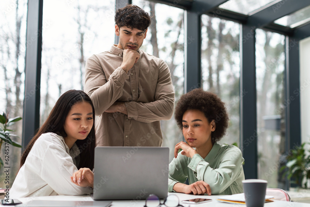 Three Business Colleagues Working Together Looking At Laptop In Office Three Business Colleagues Working Together Looking At Laptop In Office