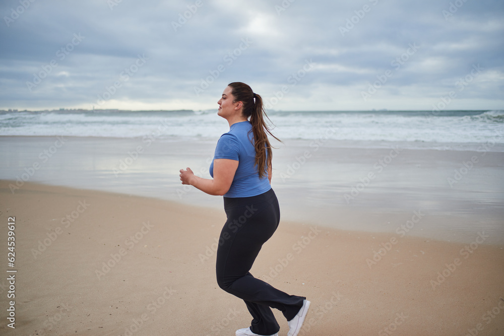 Young body positive sports woman running along the sandy sea shore Young body positive sports woman running along the sandy sea shore