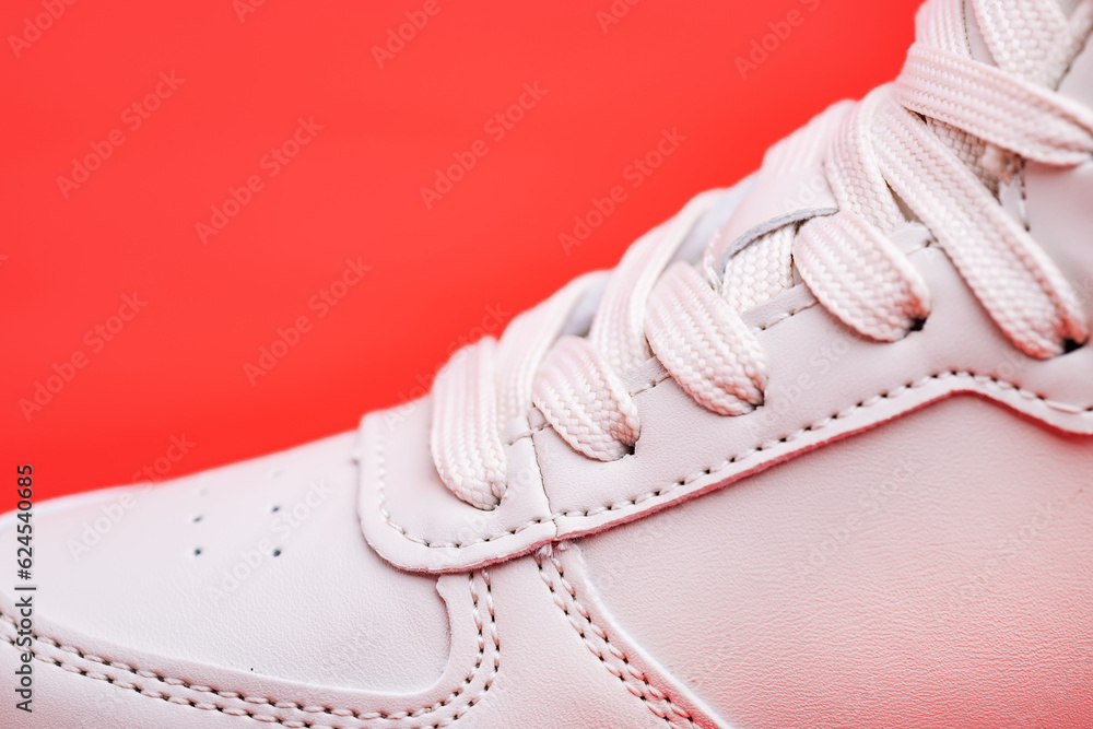 Laced fastening of new sports shoe close-up. Elastic laces of modern textile trainers for active lifestyle, sport, and fitness on red background. Copy space. Laced fastening of new sports shoe close-up. Elastic laces of modern textile trainers for active lifestyle, sport, and fitness on red background. Copy space.