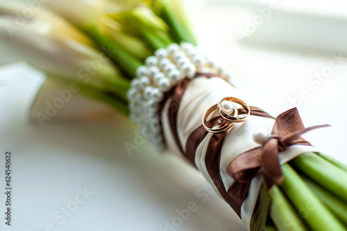 Pair of rings on the wedding  bouquet, Green flower stems are tied with a brown ribbon