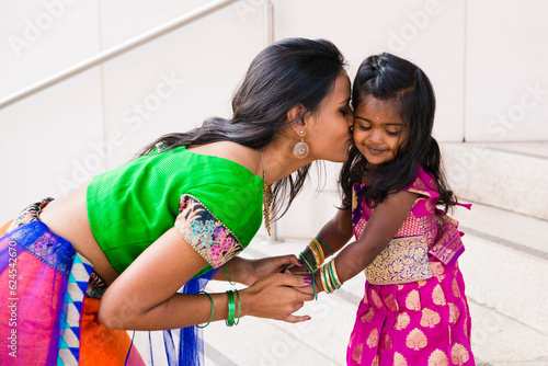 фотографія beautiful indian family mom mother with daughter girl holding hands kissing and
