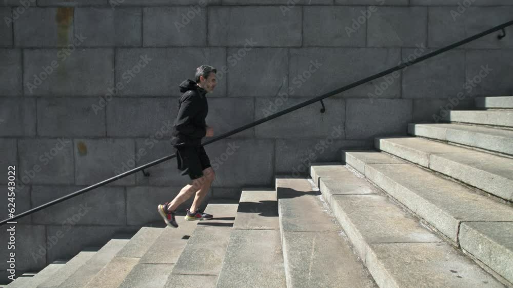 Male athlete running by stairs outdoors during workout. Sport Motivation. 40s Male Athlete Running Up On Urban Stairs Outdoors, Enjoying Morning Workout Slow Motion Male athlete running by stairs outdoors during workout. Sport Motivation. 40s Male Athlete Running Up On Urban Stairs Outdoors, Enjoying Morning Workout Slow Motion