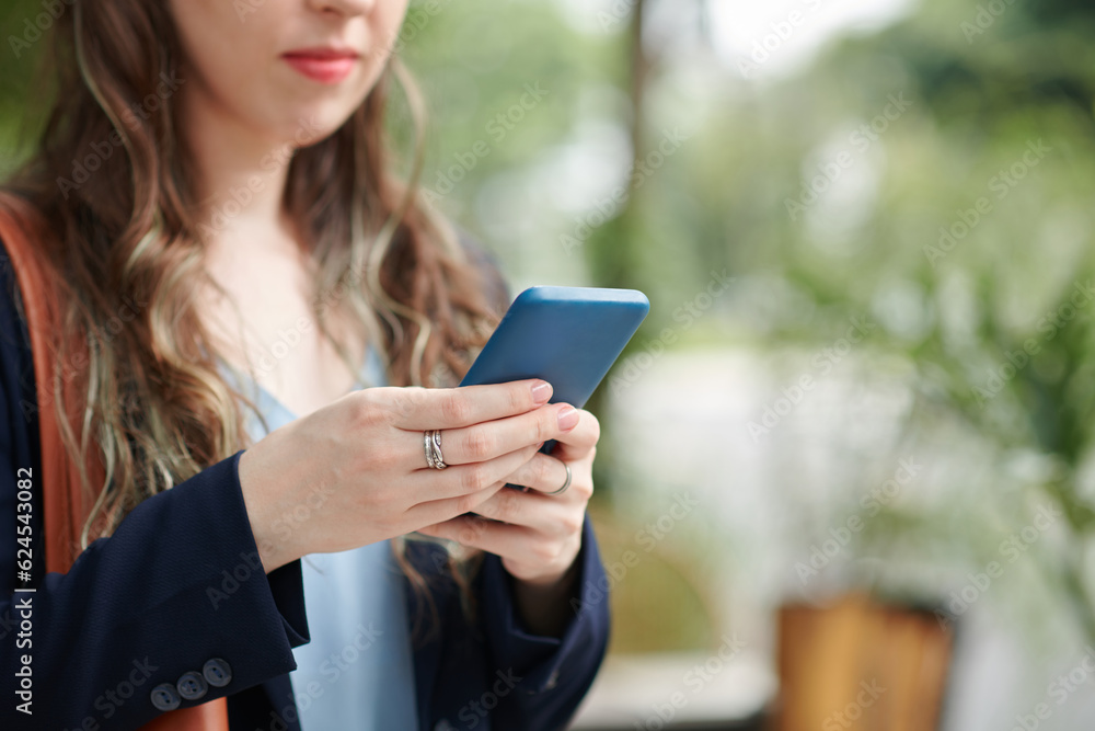 Cropped image of serious businesswoman answering text messages from coworker or reading notifications Cropped image of serious businesswoman answering text messages from coworker or reading notifications