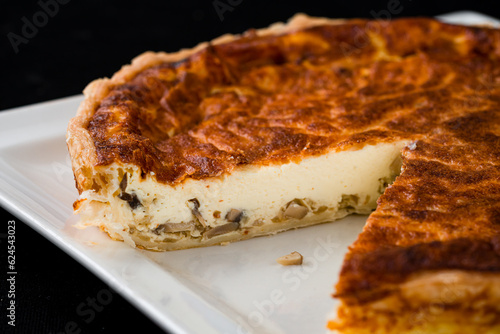 Cut baked cheese pie with mushrooms in a white plate.