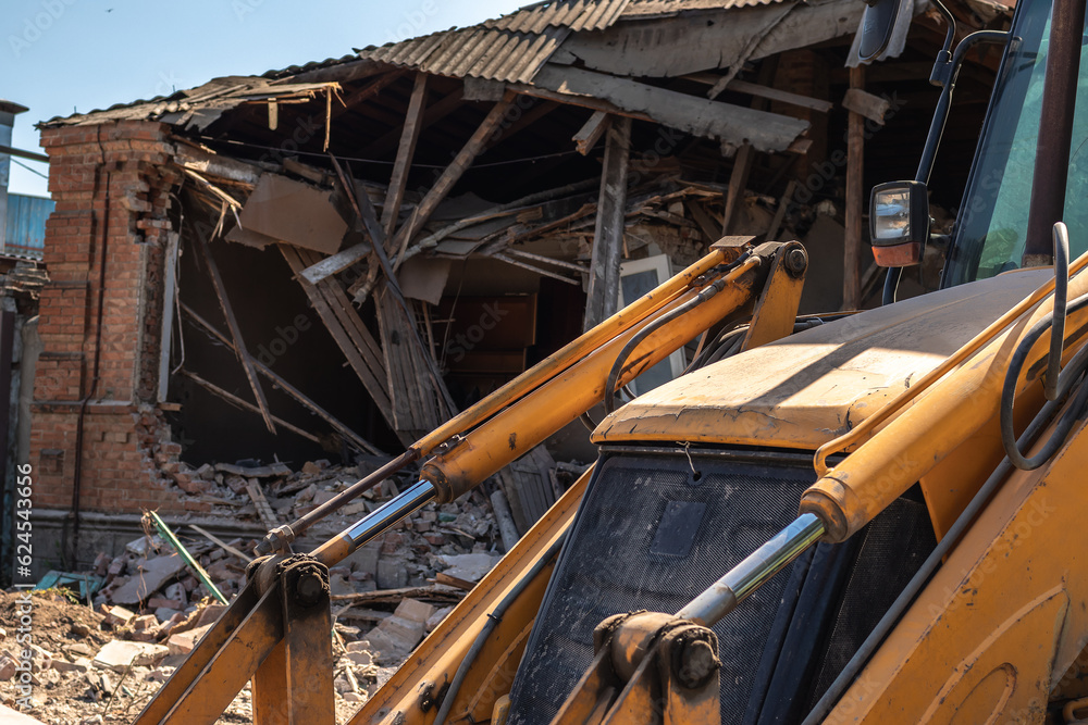 bulldozer bucket on the background of a destroyed house