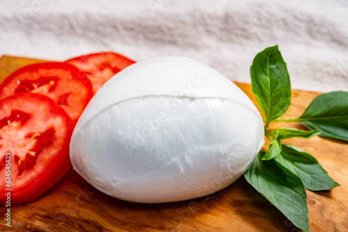 Сheese collection, one big ball on soft white italian mozzarella bufala campania cheese with green basil and red tomatoes photo