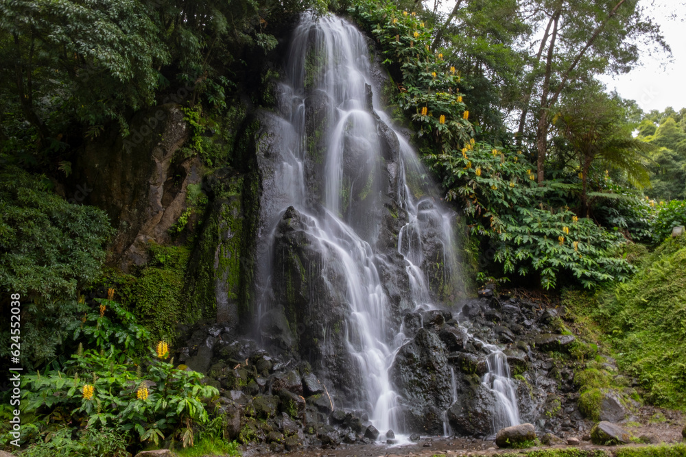 Waterfall in the Botanical Garden of Ribeira do Guilherme in Nordeste with tourists, Sao Miguel island in the Azores.