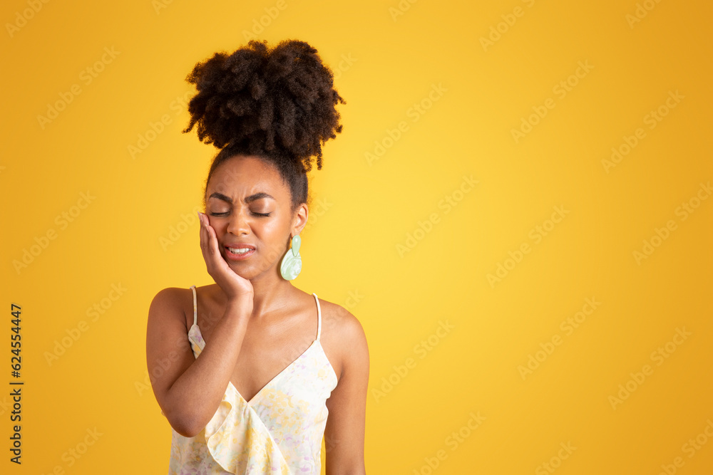 Despaired young black woman with closed eyes presses hand to cheek, suffering from toothache Despaired young black woman with closed eyes presses hand to cheek, suffering from toothache