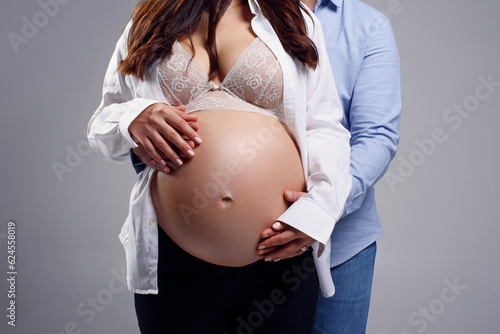 Pregnant woman and her husband holding hands together on her belly. Happy pregnancy concept.
