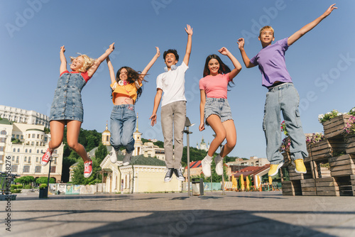 Group of multiracial overjoyed friends, happy teenagers jumping high, having fun, Happy girl and boys celebration summer holidays on the street. Friendship, positive lifestyle, summer concept 