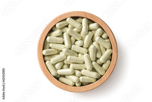 Top view of Herb capsules in wooden bowl on white background.