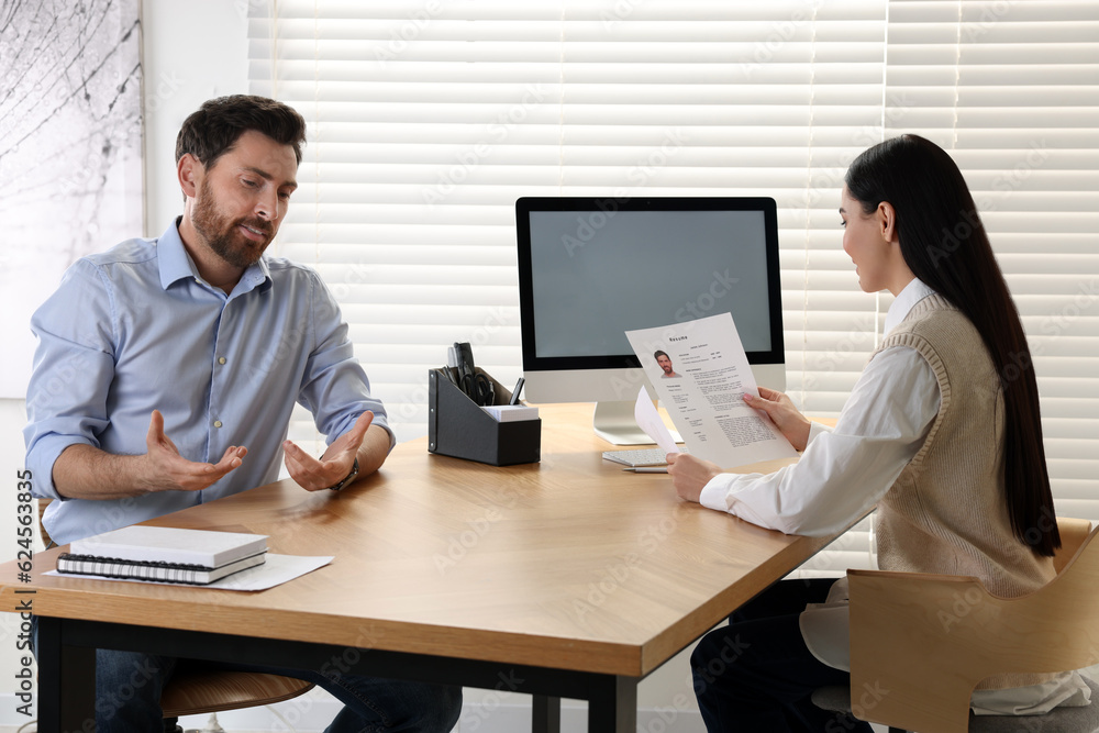 Human resources manager reading applicant's resume during job interview in office Human resources manager reading applicant's resume during job interview in office