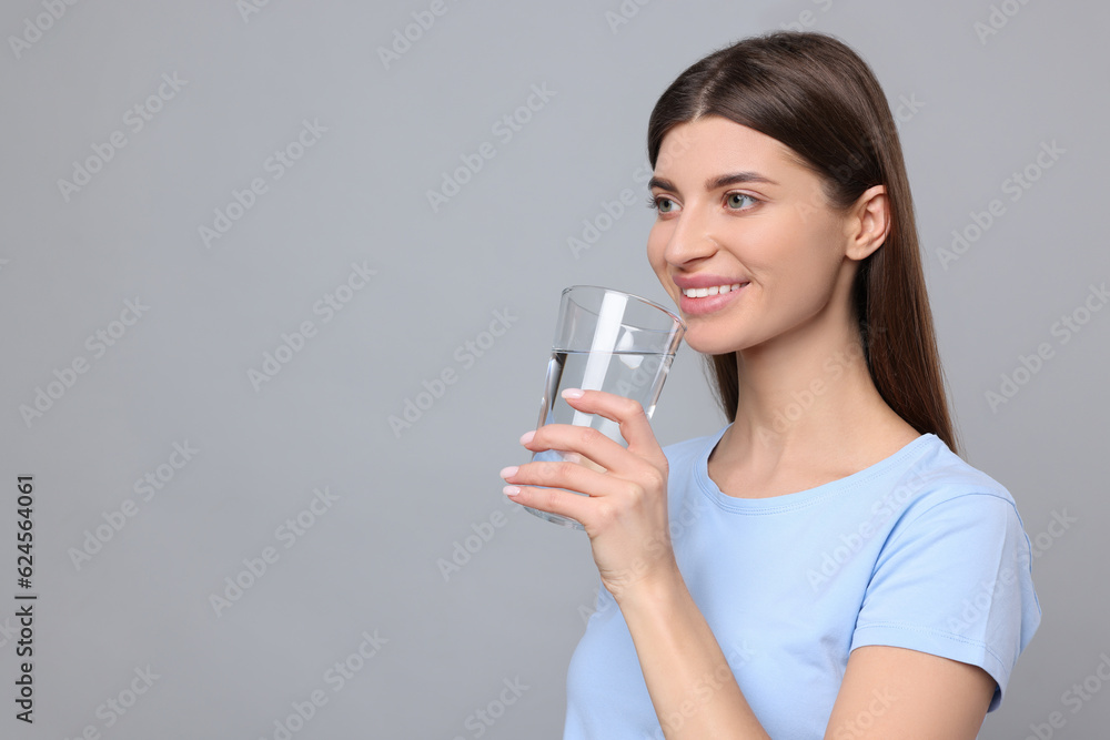 Healthy habit. Woman holding glass with fresh water on grey background. Space for text Healthy habit. Woman holding glass with fresh water on grey background. Space for text