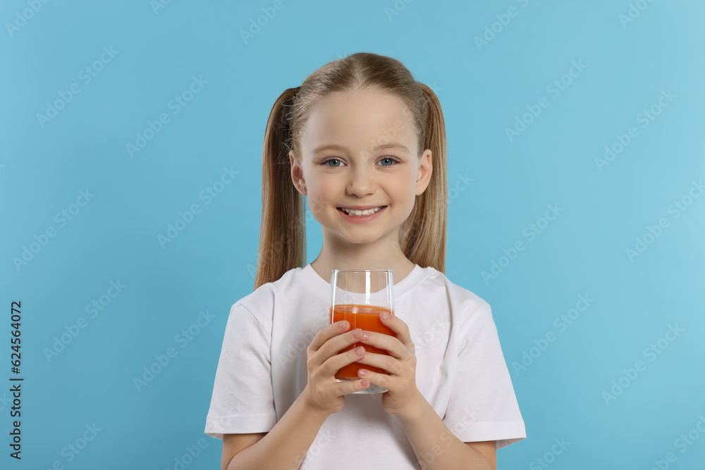 Cute little girl with glass of fresh juice on light blue background Cute little girl with glass of fresh juice on light blue background