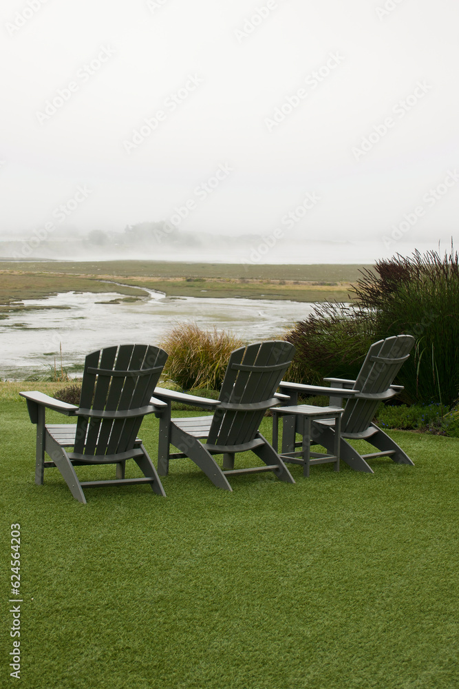 Adirondack chairs on lawn overlooking the foggy coast