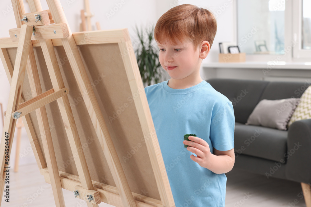Little boy painting in studio. Using easel to hold canvas Little boy painting in studio. Using easel to hold canvas
