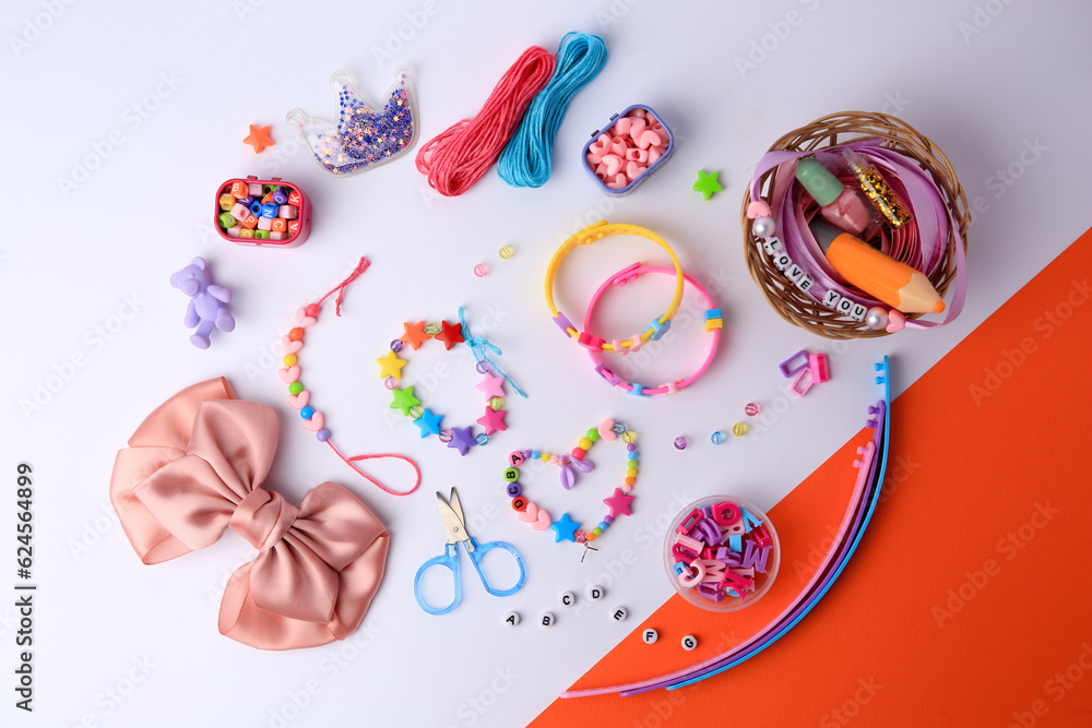 Kid's handmade beaded jewelry and different supplies on color background, flat lay