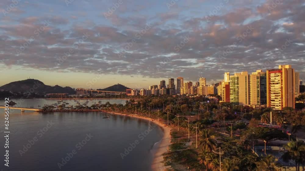 Vista aérea de drone de um amanhecer na Praia do Canto, Vitória, Espírito Santo, Brasil, captando pessoas usando uma canoa havaiana.