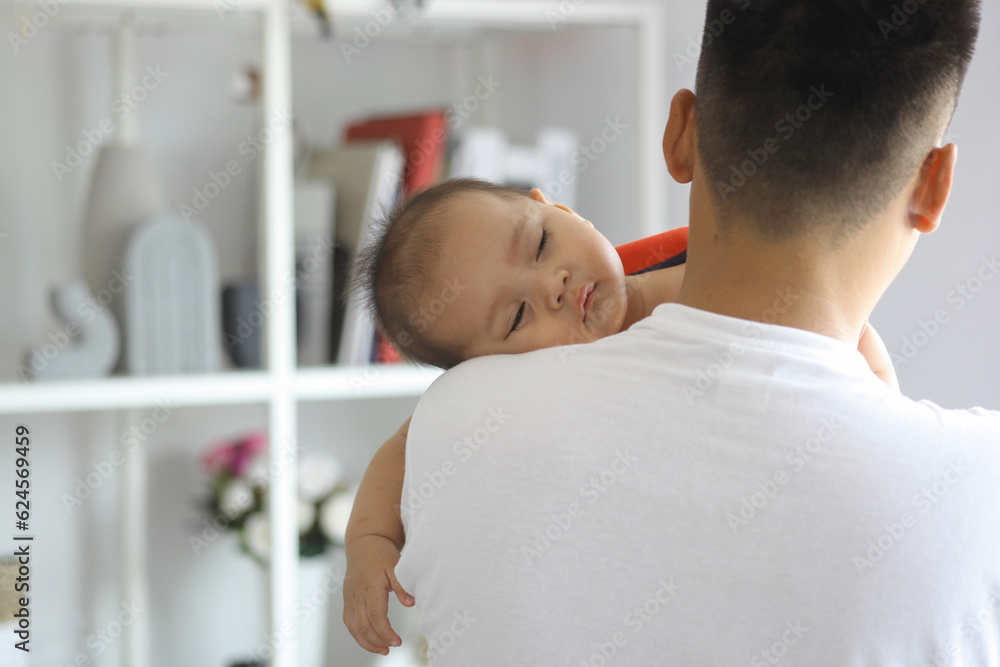 Obraz premium Cute sleepy new born baby over his fathers shoulders. Fatherhood and loving care concept