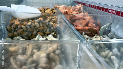 Frozen King prawns or royal shrimps and mussels in a display fridge in a supermarket photo