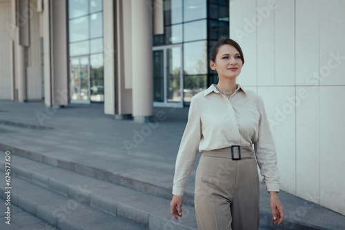 Young caucasian woman in business style walking out of the office building for lunch.