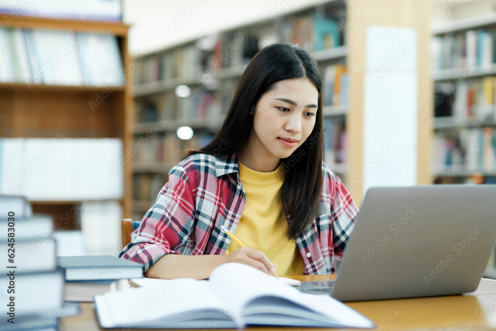 Young university student using laptop for online learning, searching and learning at library. Young university student using laptop for online learning, searching and learning at library.