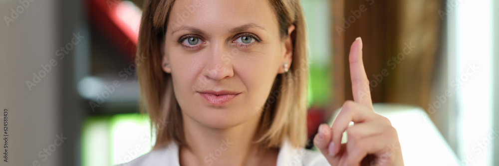 Female doctor pointing her finger up in medical office. Female doctor pointing her finger up in medical office.