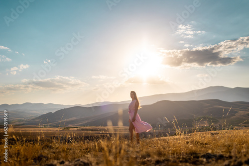 young girl in a pink dress enjoys a walk in the mountains.