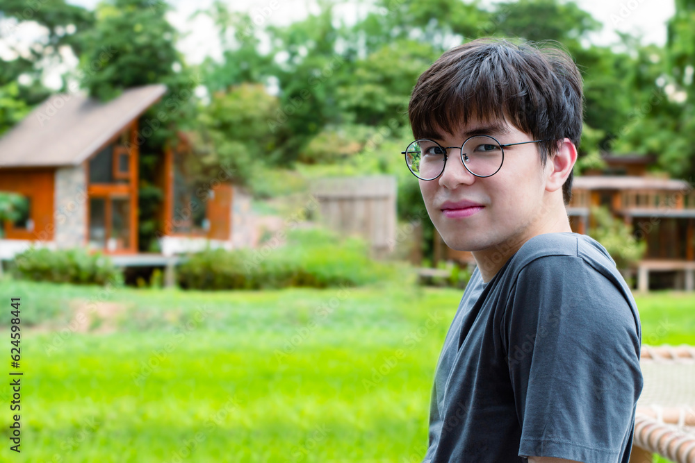 Portrait of young asian adult cute boy wearing headphones, sitting, listening to music and spending free time in front of his house, good feelings and best emotions concept. Portrait of young asian adult cute boy wearing headphones, sitting, listening to music and spending free time in front of his house, good feelings and best emotions concept.